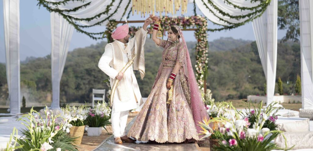 Bride Bismin and groom Arsh walking together during Anand Karaj laavan ceremony under floral mandap