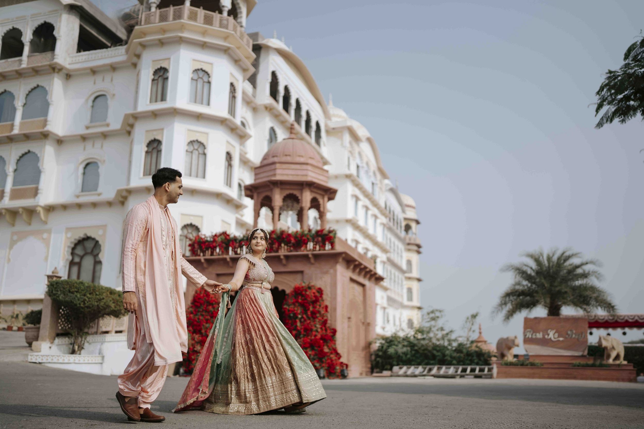 Bride and groom posing in front of grand palace façade during destination wedding