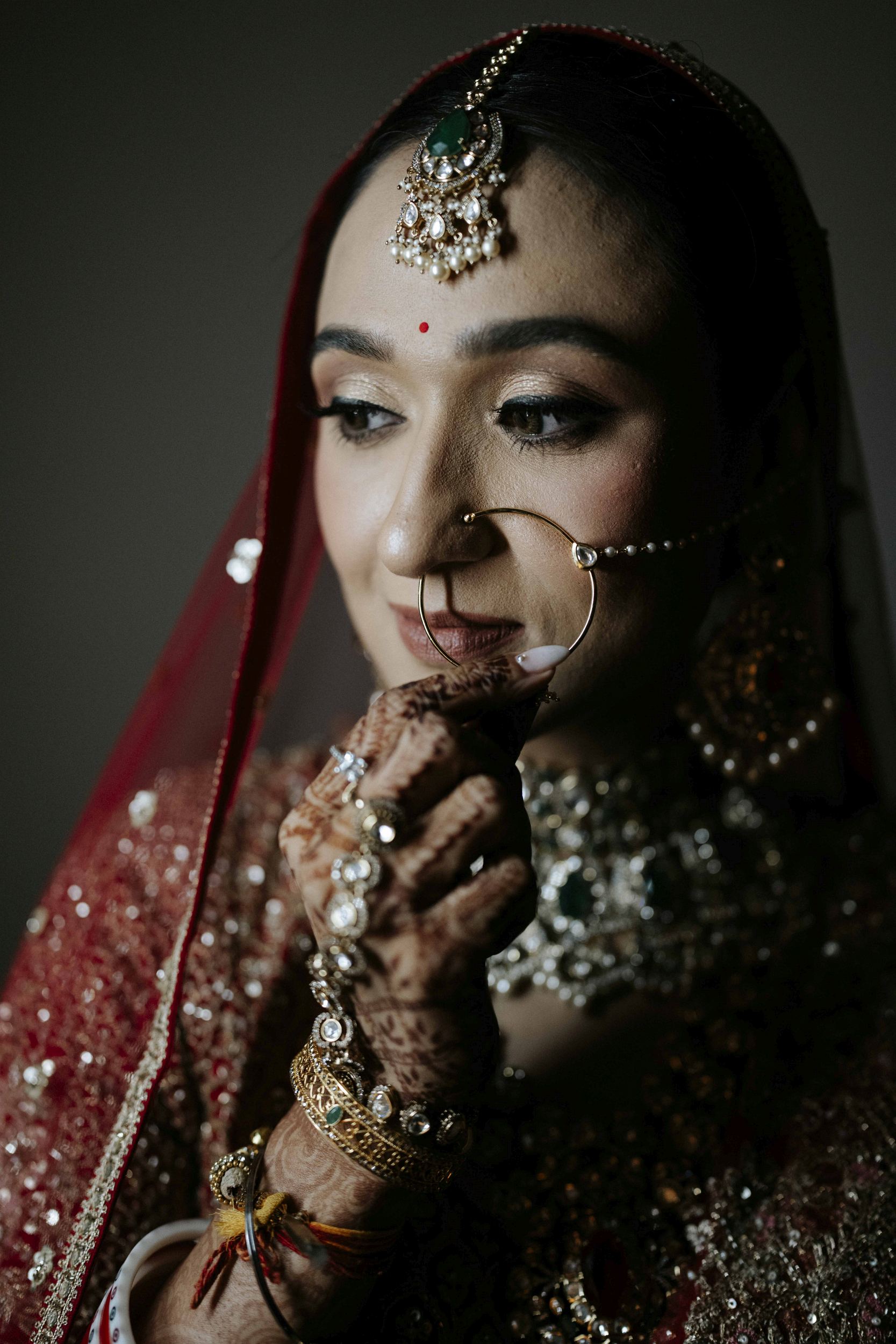 Bridegroom portrait showing her red saree, nose nath and tikka jewelery